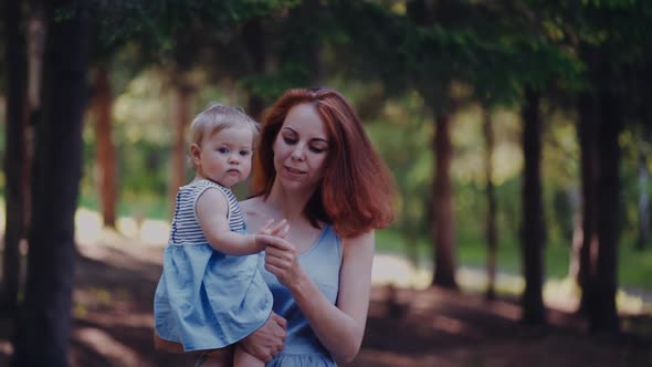 mom holds the baby in her arms walking in the forest or in the park