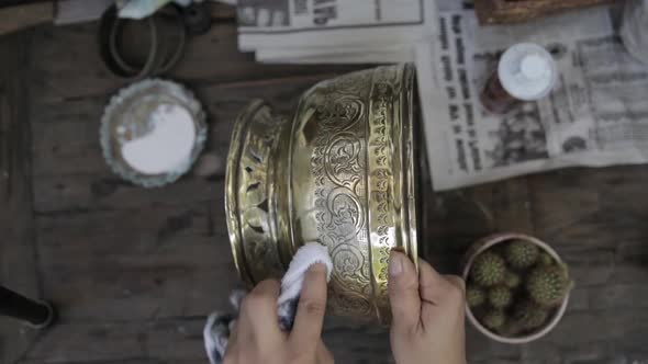 Restoration process. Antique dealer is polishing and restoring an old golden bowl.