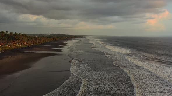 aerial dolly zoom out of empty black sand beach in Bali Indonesia during sunset