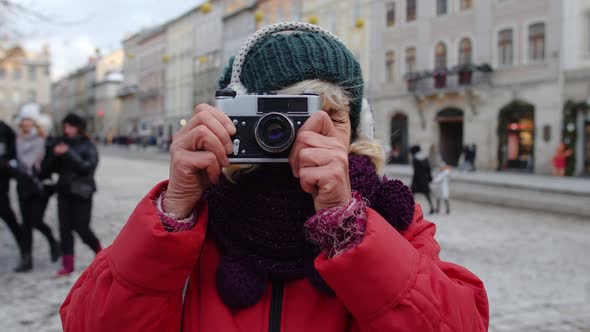 Senior Old Woman Tourist Taking Pictures with Photo Camera Using Retro Device in Winter City Center