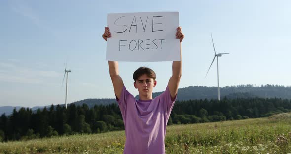 Outdoor of Men Activist with Save Forest Ecology Poster. In Background Forest and Wind Turbine