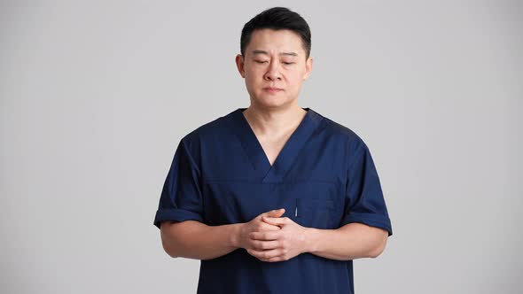 Sad Asian doctor talking something at the camera