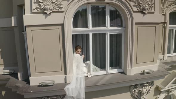 Bride in Boudoir Dress Sitting on Window Sill Wedding Morning Preparations Woman in Night Gown Veil