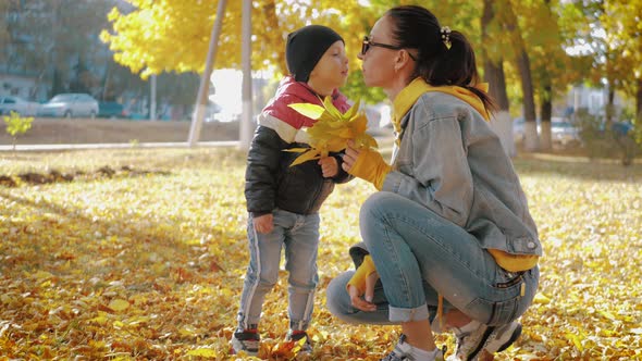 Mom Playing with Son in Autumn Park. Happy Moments Together. Family in the Autumn Park.