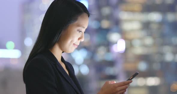 Businesswoman working on cellphone in city at night 