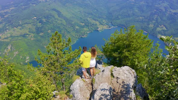 Aerial View on Couple Standing Against Amazing Nature View on Mountain Lake in on the Border of