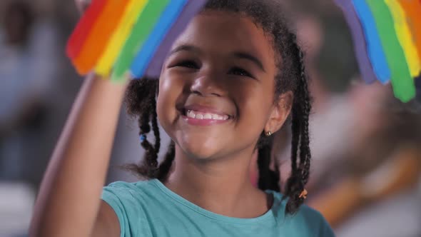 Smiling Girl Painting Rainbow on Window Pane