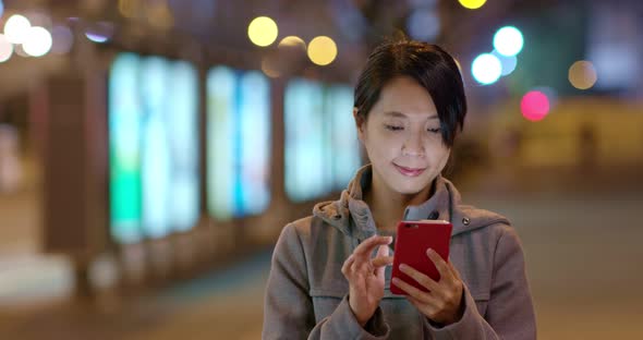 Woman use of cellphone online in the city at night