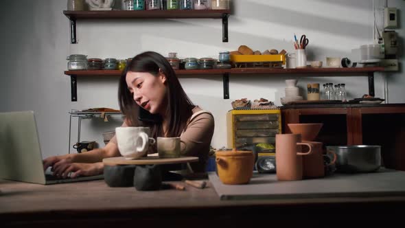 A young female ceramicist is busy checking orders for ceramics for a customer.