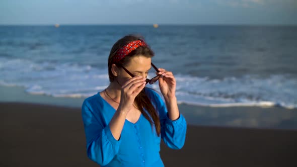 Portrait of a Woman in a Beautiful Blue Dress on a Black Volcanic Beach. Slow Motion