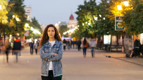 Time-lapse Portrait of Lonely Young Lady Standing in Street Downtown with Arms Crossed While Crowds