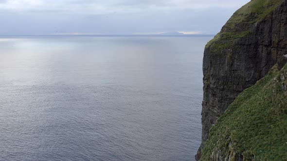 Drone Passing Asmundarstakkur Sea Stack Towards Horizon