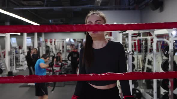 Young Pretty Woman Walks To a Boxing Ring in the Gym