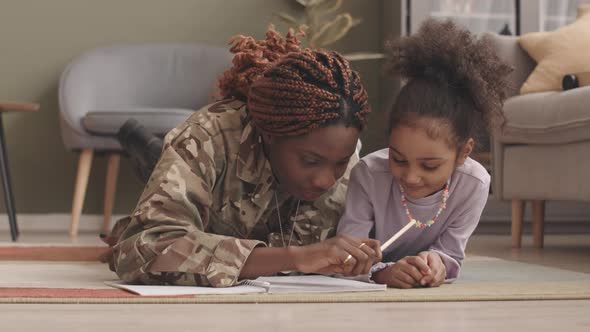 Military Woman and Her Little Daughter Drawing Together at Home alt