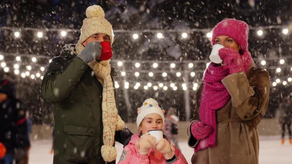 Happy Family Drinking Hot Tea on Skating Rink