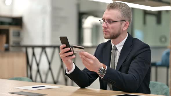 Businessman Making Successful Online Payment on Smartphone in Office