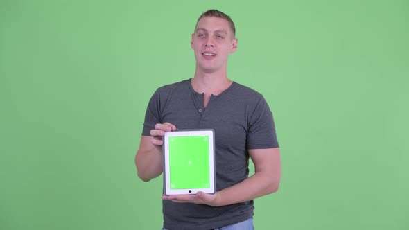 Happy Young Man Talking While Showing Digital Tablet