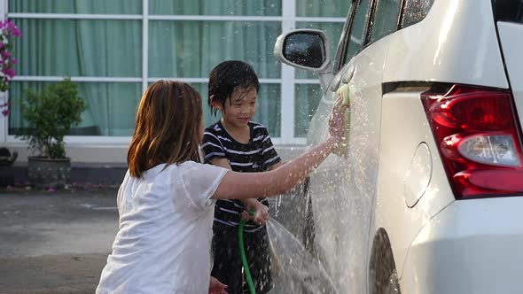 Asian Mother And Son Washing Car Together On Summer Day