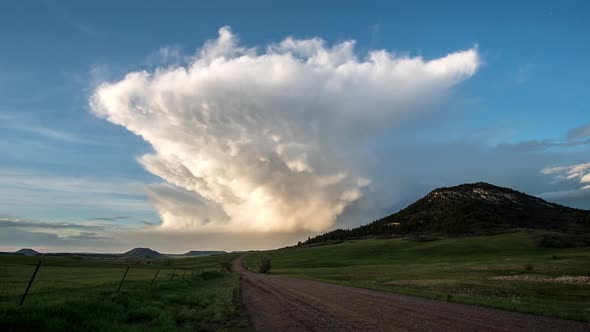 Time lapse looking down dirt road towards tall cloud structure