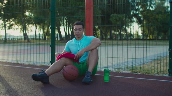 Tired Basketball Player Resting After Game at Court