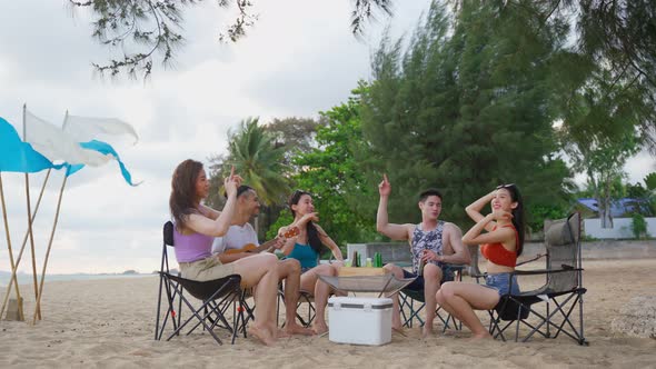 Group of Asian young man and woman having party on the beach together.