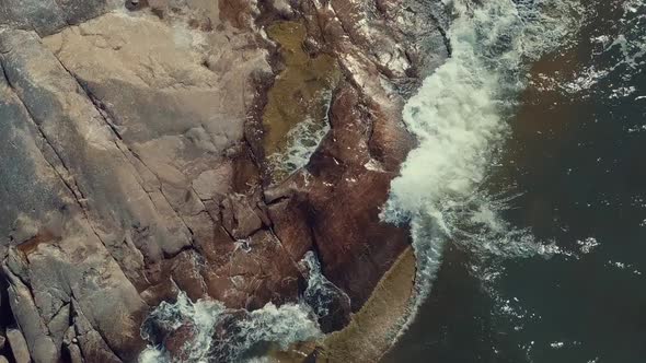 waves hitting rocks at a beach drone footage
