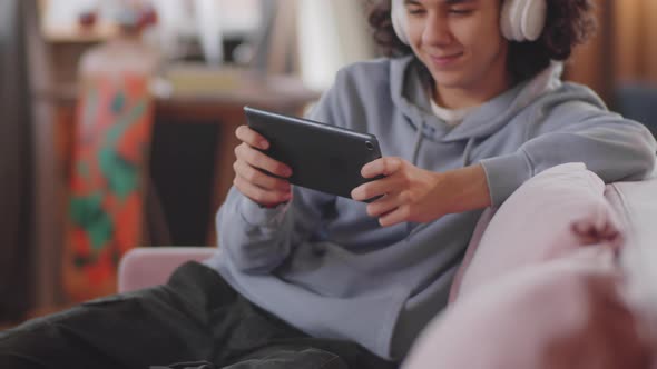 Cheerful Teen Boy Playing Video Game on Tablet