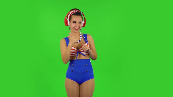 Beautiful Girl in a Swimsuit Is Dancing and Enjoying Music in Big Red Headphones. Green Screen