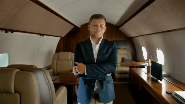 Confident Business Man with Crossed Arms Inside of Private Jet Seriously Looking at You