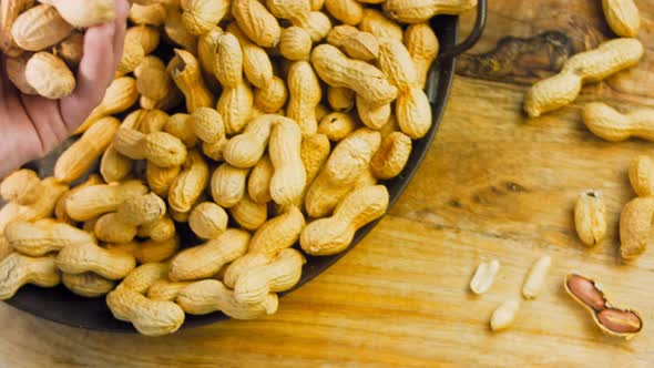 The Woman Analyzes the Quality of Peanuts with Bark