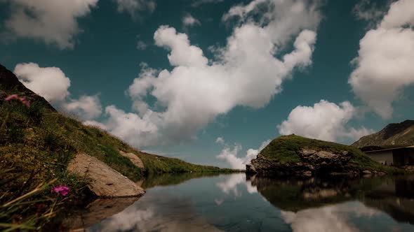 Small glacial lake located between the mountains with clouds reflection