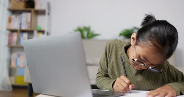 Happy girl kid studying online in living room