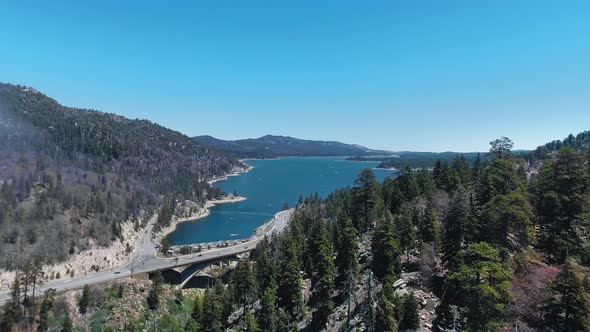 The drone flies over the road that goes along the shore of Big Bear Lake, California, USA