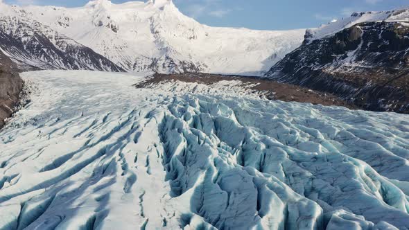 Drone Over Large Glacier With Snow Covered Mountains