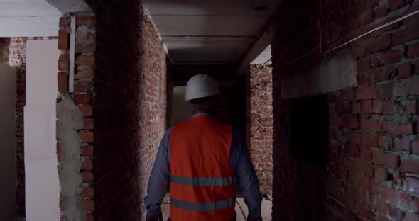 Following Shot of Unrecognized Professional Factory Worker Wearing Hard Hat Walking Thorugh