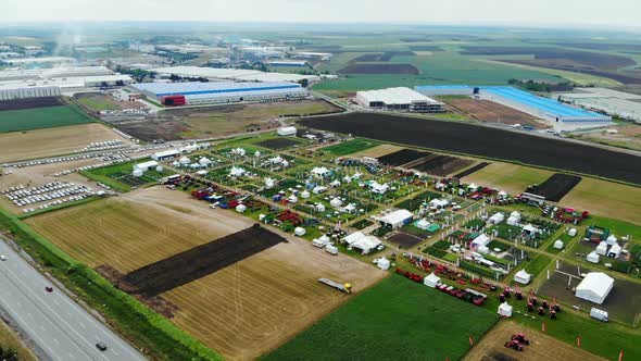 Drone Shot with Ascending Top View of Agricultural Expo Fair on Green Fields of Farm Lands with Fact