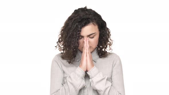 Portrait of Serious Young Woman Holding Hands Together and Asking God for Good Luck Over White