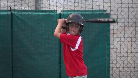 A boy practices baseball at a batting cage.