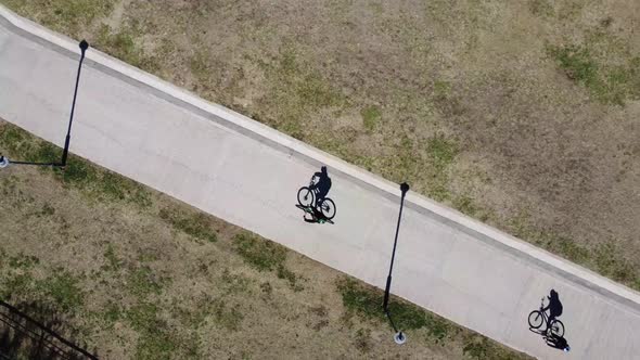aerial footage of two cyclists on an asphalt road