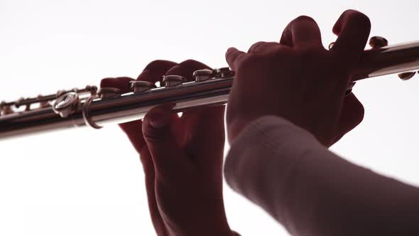 Musician's hands touch the keys of the flute, close-up. Female musician plays flute