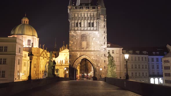 A gate tower on one side of Charles bridge in the historical city centre of Prague, lit by the golde