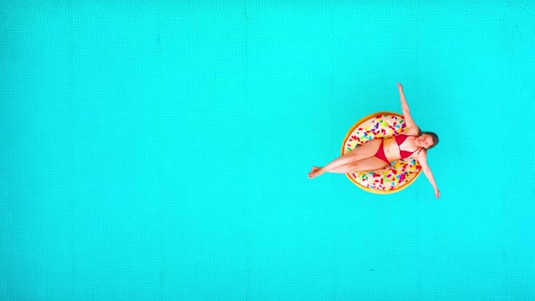 Aerial View of a Woman in Red Bikini Lying on a Donut in the Pool