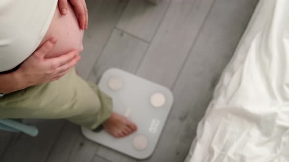 Young Woman Measuring Her Pregnant Weight Standing on Scales