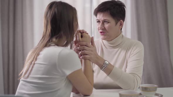 Beautiful Caucasian Mother Holding Adult Daughter's Hands and Talking. Attractive Lady Soothing