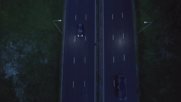 Aerial drone view of a multi-level highway crossroad with moving cars at sunset. Cars are moving alo