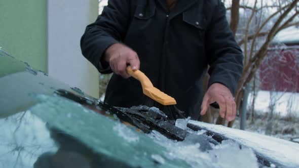 Person Holds Brown Wooden Snow Brush and Cleans Ice