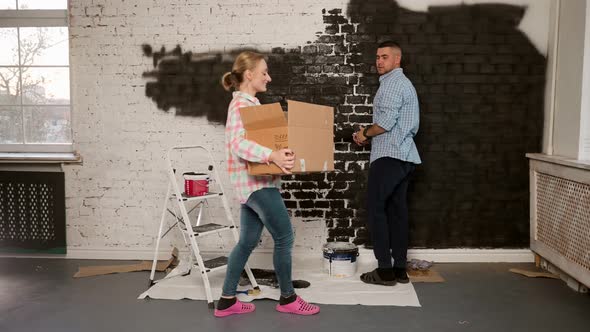 Young Happy Couple Sitting on the Floor of Their New Appartment and Planning Redecoration