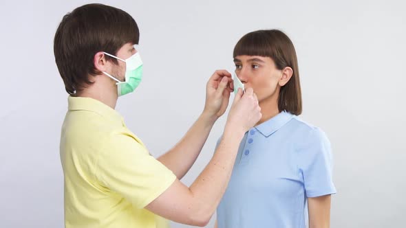 Handsome Young Man in Yellow Shirt Putting on Lovely Girl Sterile Protection Mask To Avoid