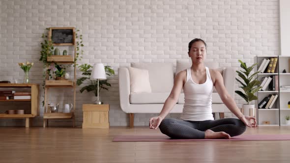 Asian woman practice yoga lotus pose to meditation at home.