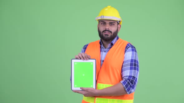 Happy Young Overweight Bearded Indian Man Construction Worker Talking While Showing Digital Tablet